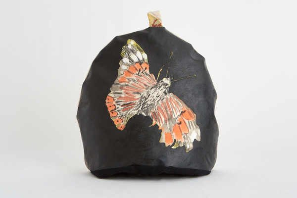 black tea cosy revealing a colourful butterfly
