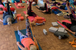 a goup of people lying down on yoga mats with their right leg in the air
