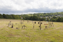 a field with a circle of sculptures made from sticks and found objects