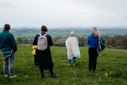 three people standing with their back to us looking our over a expansive view of hardington