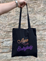 black tote with orange and purple text which read Alone with everybody in a script typeface